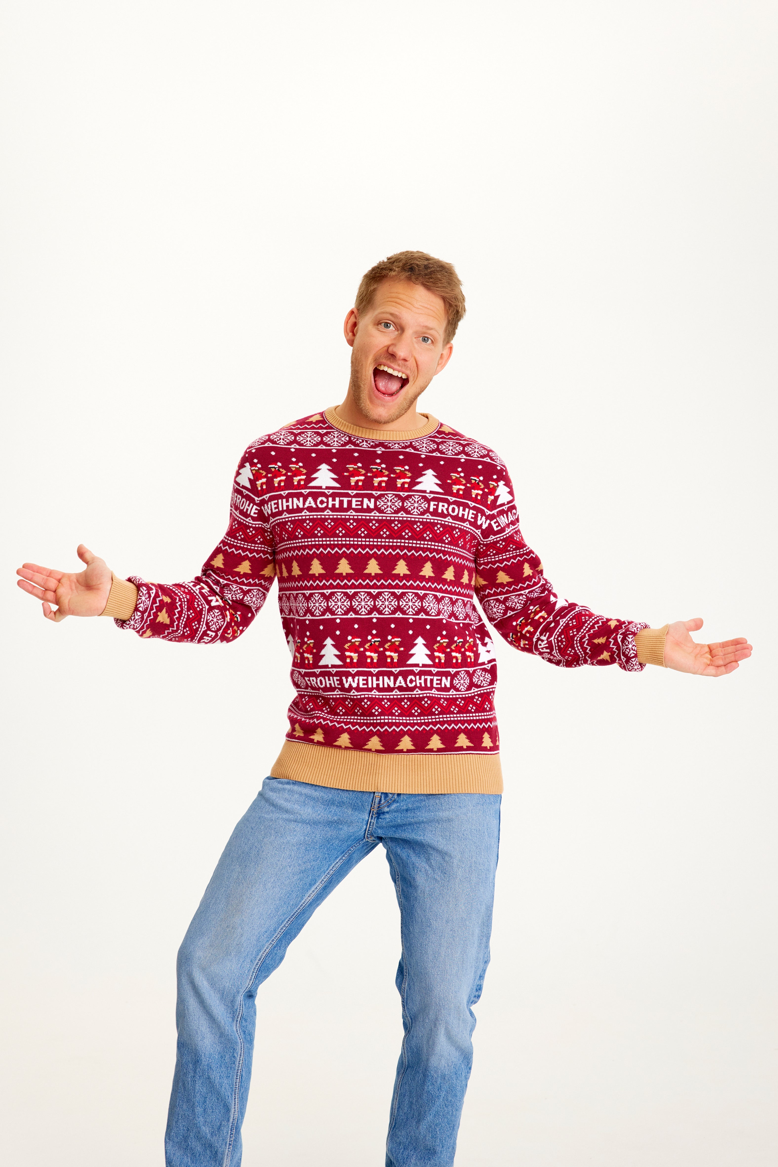 Un homme posant portant un pull de Noël rouge à motifs.